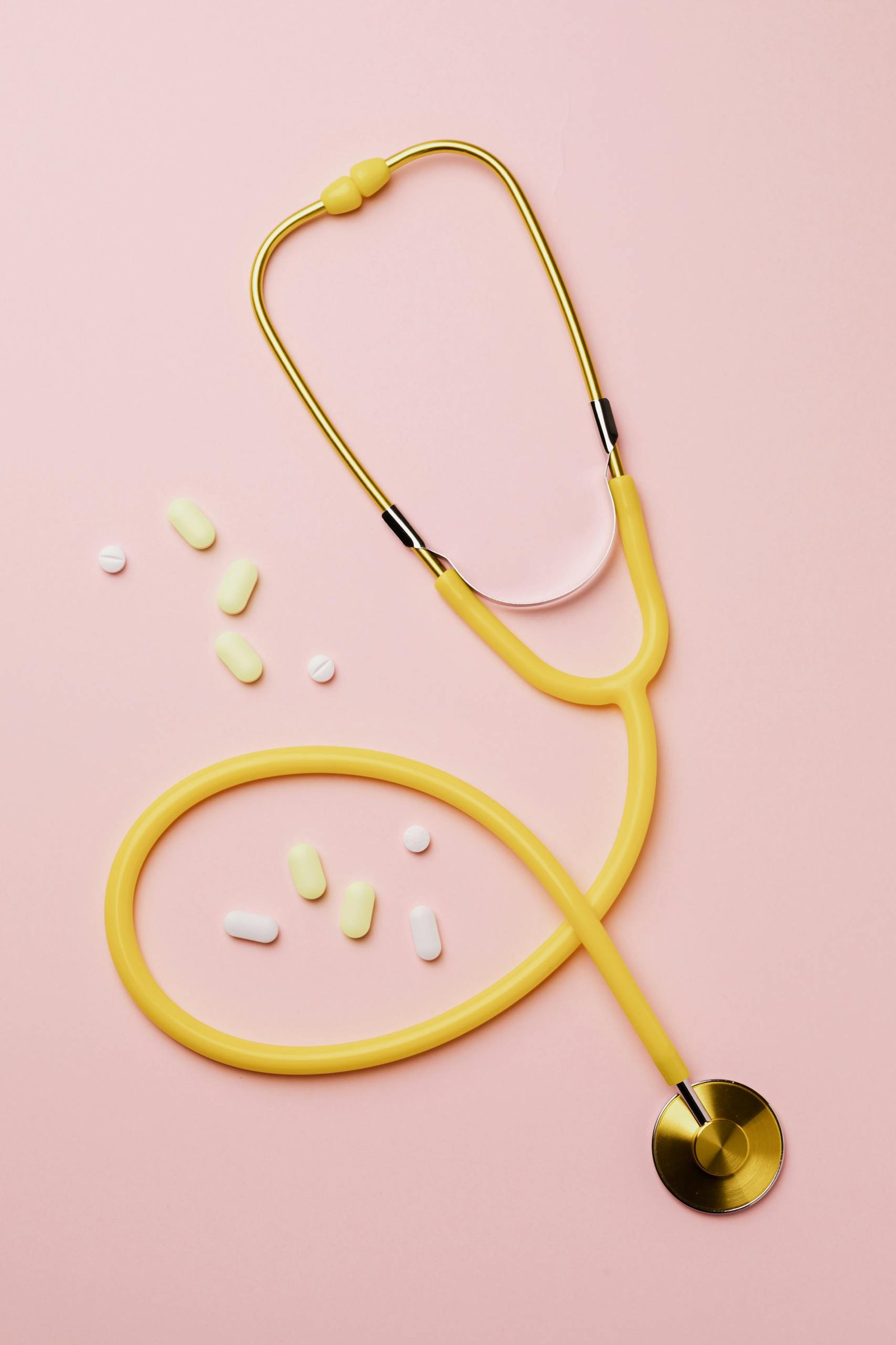 Yellow Stethoscope And Medicines On Pink Background